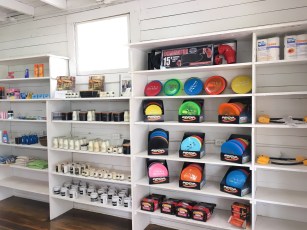 Brightly colored disc golf discs and equipment displayed on white shelves in a retail store